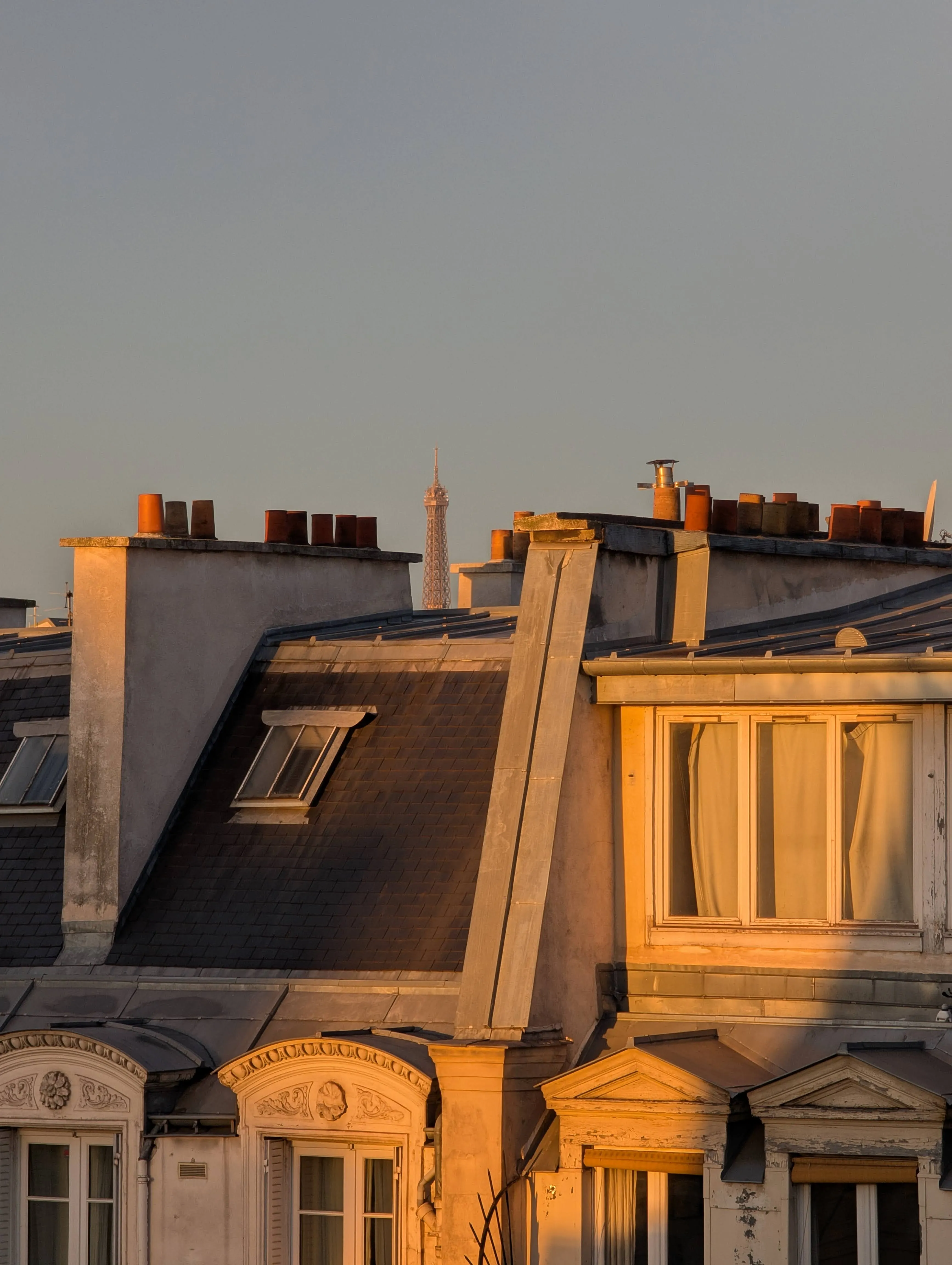 In between the various roofs, the top of the Eiffel tower is peeking through.