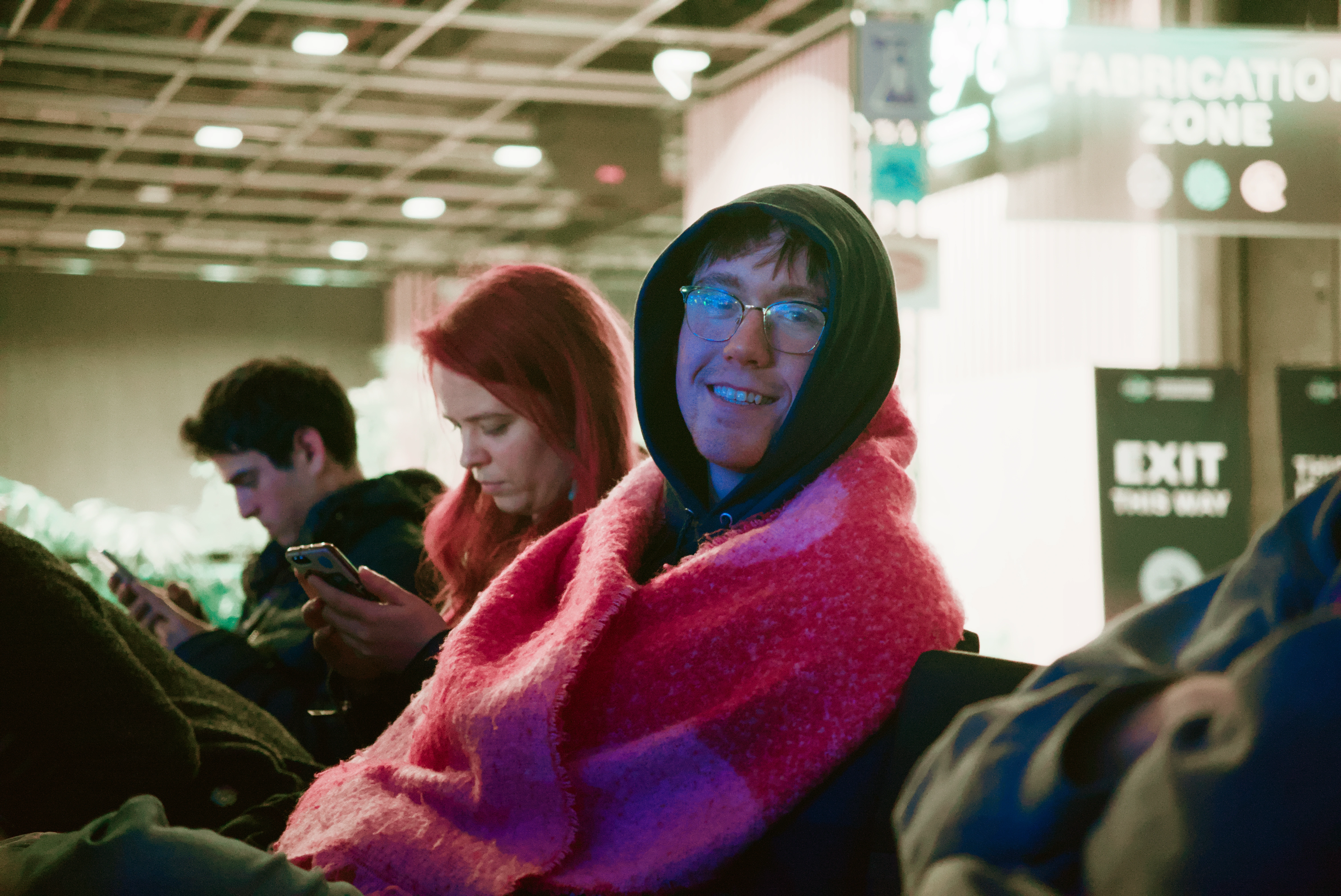 A TRAPS member sitting in front of the stage, wrapped in a thick scarf.