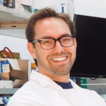 Christopher Emig in a lab coat smiling.