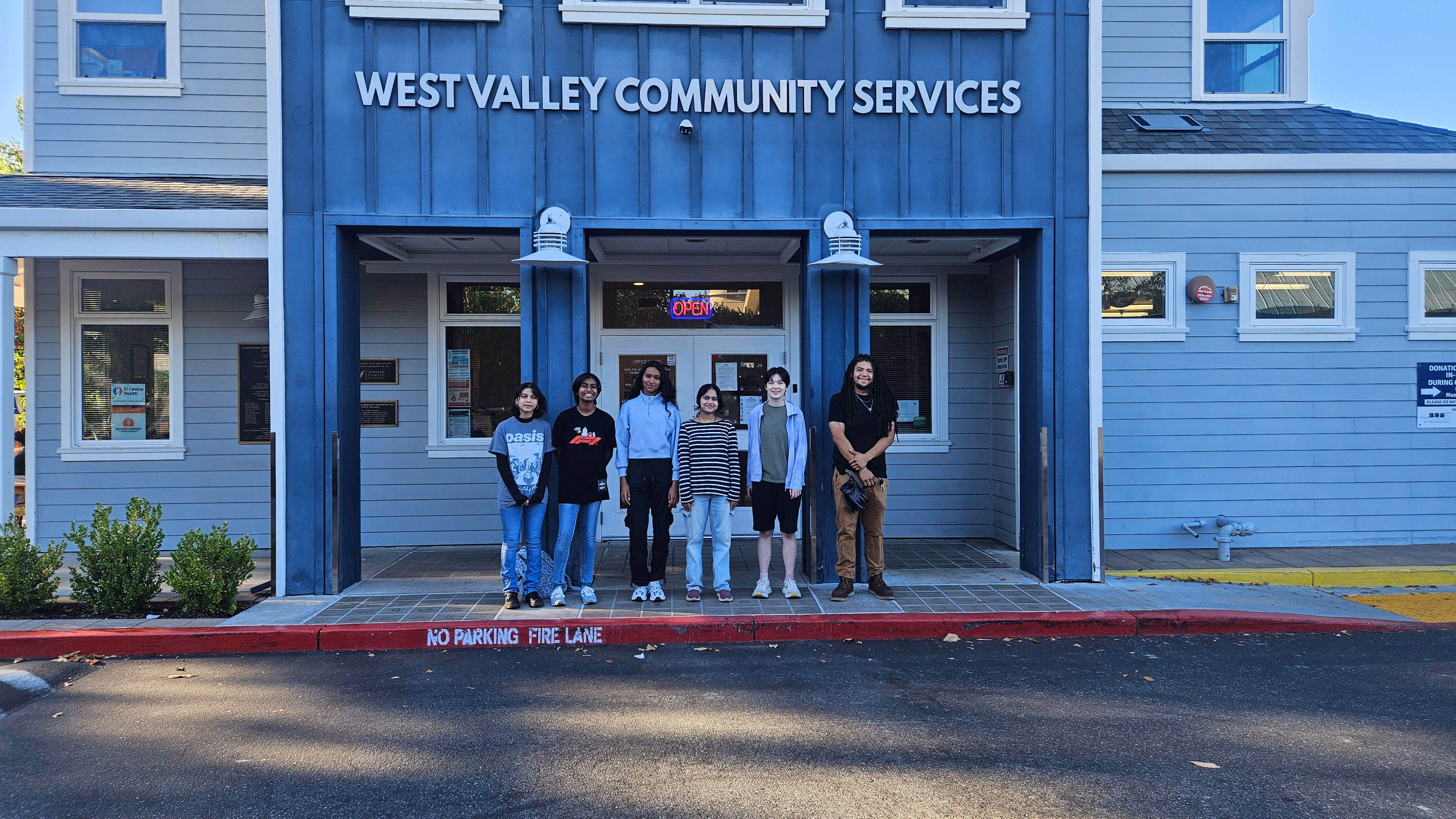 Team members and Chris Coleman standing in front of a building labeled West Valley Community Services.